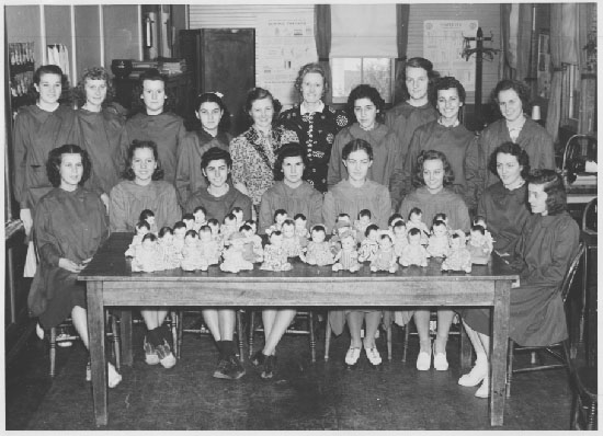 18 women showing dolls for donation