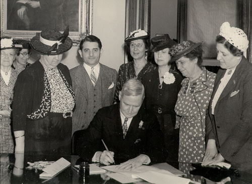 governor signing while being observed by leaders of Women's orgaizations