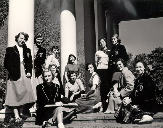 11 women posed in near columns in front of some Douglass campus building
