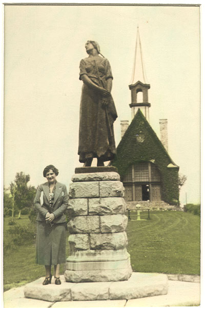 Hazel Hackett in serious tweed suit by monument
