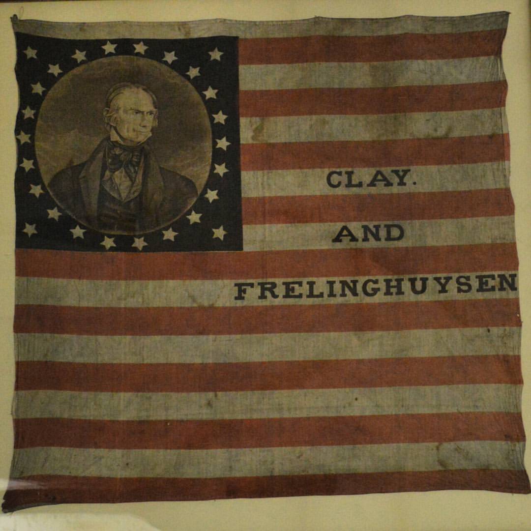 Clay & Frelinghuysen campaign flag, 1844. square 17 red and white stripes, photo of Clay in blue field with stars